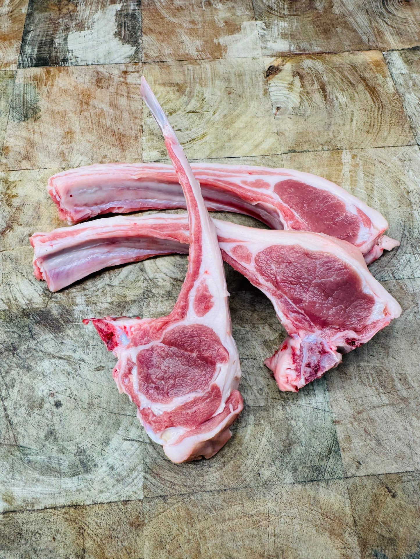 Côtes d'agneau fraîches sur planche en bois, origine France, 125g, prêtes pour cuisson rapide.