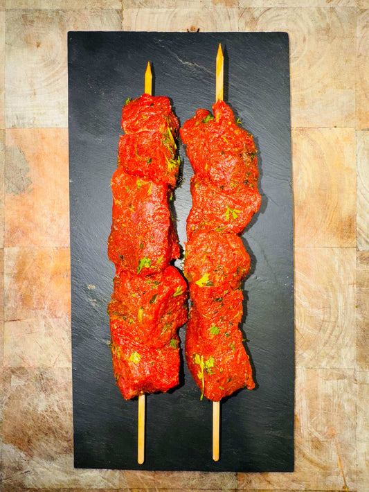 Brochette de bœuf marinée, originaire de France, présentée sur une planche noire.