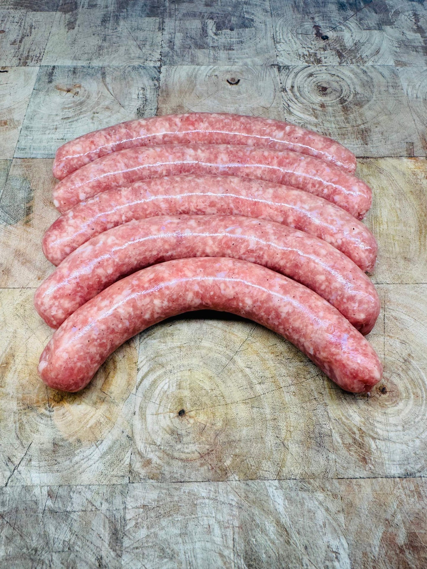 Chipolatas françaises 500g sur planche en bois, savoureuses et légères.